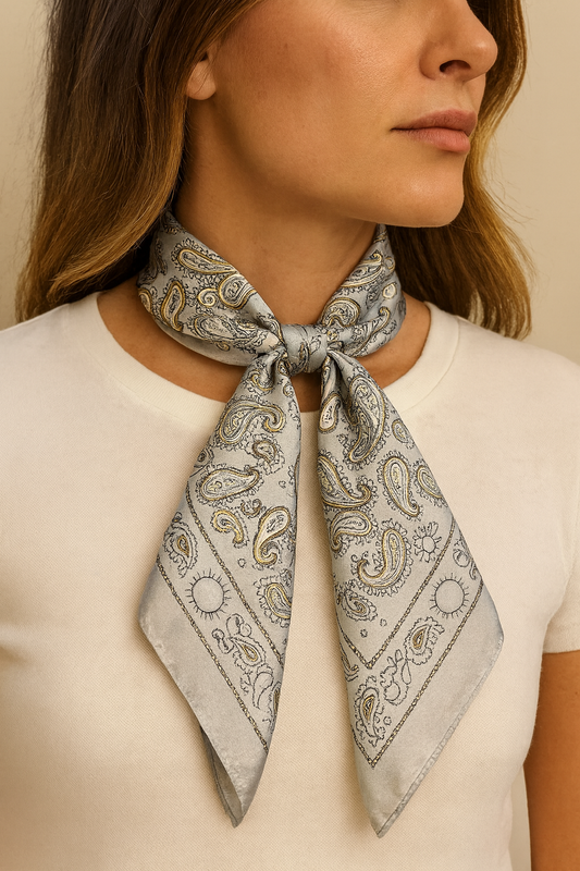 Woman wearing a gray paisley scarf around her neck against a beige background