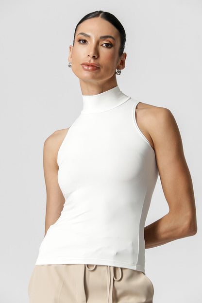 Woman wearing a white sleeveless top against a plain background
